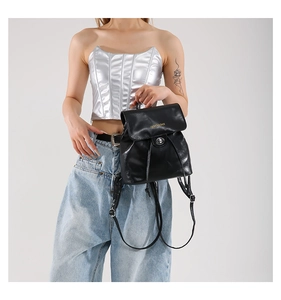 Detail of black glossy PU leather mini backpack with silver turn-lock and gold lettering