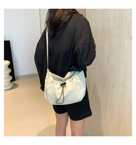 Detail van crème crossbodytas met trekkoord en verstelbare brede schouderriem