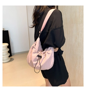 Detail of pink drawstring crossbody bag with wide shoulder strap and cloud-like pleats