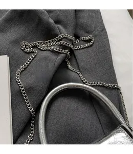 Detail of silver metallic textured crossbody bag with sleek chain strap and handle
