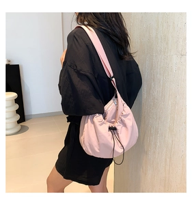 Detail of pink pleated cloud bag featuring functional drawstring and adjustable shoulder strap