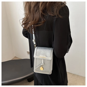 Dettaglio mini borsa a tracolla argento con scritta Tidal Dryness dorata e nappa
