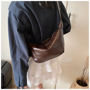 Detail of dark brown crescent bag with geometric stitching on soft leather texture