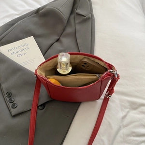 Red lychee grain crescent crossbody bag showing interior space with phone and perfume bottle
