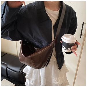 Detail of a dark brown glossy leather hobo bag showing its pleats and soft texture