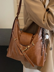Sac fourre-tout marron en similicuir vintage avec breloque baseball porté à l'épaule