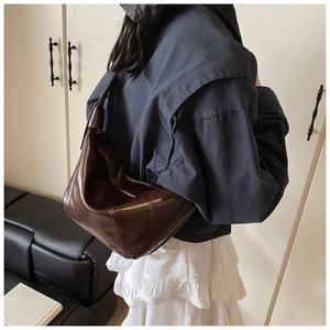 Side view of dark brown glossy leather hobo bag with pleated texture and zipper detail