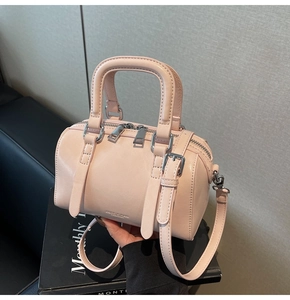 Detail of light pink Boston bag with dual handles and silver zipper closure