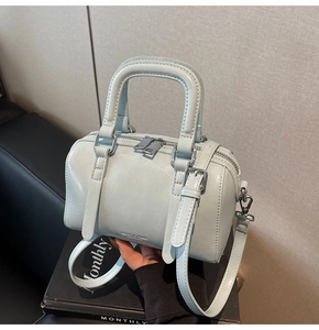 Detailed view of light blue Boston bag with leather handles and silver hardware