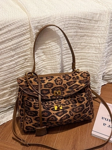 Large leopard print tote bag with gold swivel lock and adjustable strap on wood floor