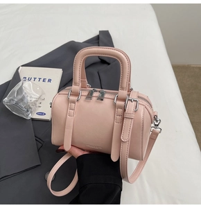 Detail of pink Boston bag with silver buckles and dual handles for crossbody style