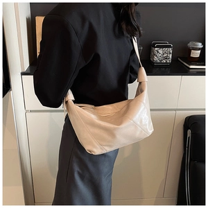 Detail of minimalist beige pleated hobo bag with geometric stitching on soft leather