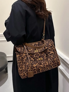 Large leopard print tote bag with brown leather trim and gold buckle shown on shoulder