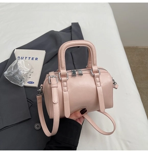 Detail of light pink Boston bag with smooth leather texture and silver hardware accents