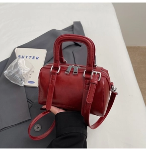 Detailed macro view of the wine red leather Boston bag with dual zippers and silver hardware