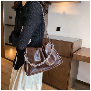 Detail of dark brown glossy wrinkled leather shoulder bag with chic silver chain strap