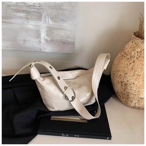 Close-up of soft cream leather pleated shoulder bag with metal horseshoe buckle detail