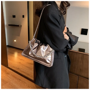 Detail of metallic silver chain strap on vintage pleated shoulder bag with mirror texture