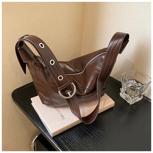 Detail of dark brown faux leather bag with adjustable strap and silver eyelet buckle