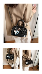 Detail of black patent leather Boston bag with embossed logo and horse charm