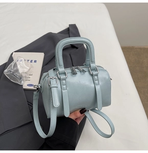 Close-up of light blue mini Boston bag on grey suit jacket showing leather texture