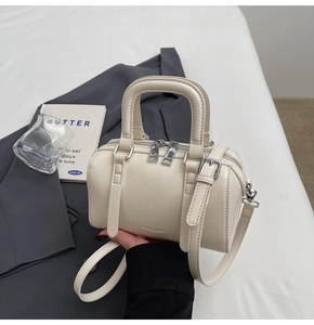 Detail of off-white Boston bag with dual zippers and silver hardware on grey blazer