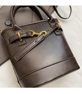 Gros plan d'un sac seau en cuir marron foncé avec boucle en métal doré et surpiqûres