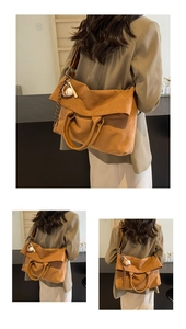 Dettaglio di una borsa tote in pelle scamosciata marrone con tracolla larga e ciondolo