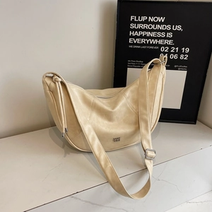 Minimalistische beige mondförmige Hobo-Tasche aus Leder mit silbernem Logo auf Marmor