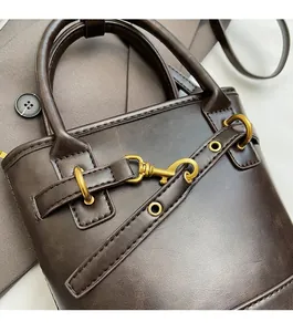 Gros plan sur un sac à main en cuir marron foncé avec boucles dorées et détails d'anneaux