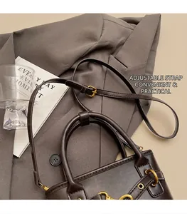 Détail du sac seau en cuir café foncé avec anneau métallique et bandoulière sur un complet