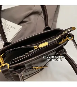 Détails d'un sac à main en cuir marron foncé avec fermeture éclair dorée et texture