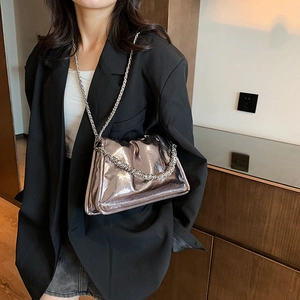 Silver metallic cloud bag with crackle texture and dual chain straps on a black blazer