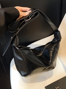 Minimalist black slouchy hobo shoulder bag with geometric patchwork and shiny finish