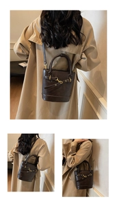 Détail d'un sac seau vintage marron foncé avec poignée ronde et accents métalliques dorés