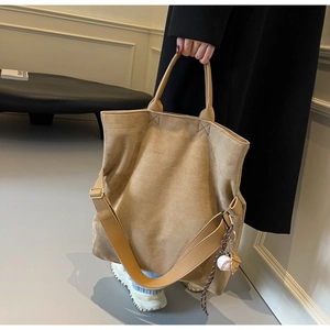 Dettaglio della borsa tote in pelle scamosciata kaki con tracolla e ciondolo baseball