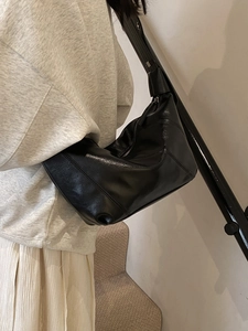 Minimalist black faux leather hobo bag with adjustable wide strap and pleated detail