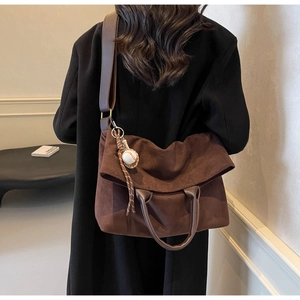 Dettaglio della borsa tote in pelle scamosciata marrone con tracolla e ciondolo