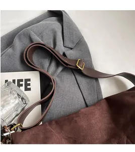 Dettaglio della borsa in pelle scamosciata marrone con tracolla regolabile e fibbia oro