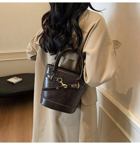 Détail du sac seau vintage marron foncé avec boucle en métal doré et texture lisse