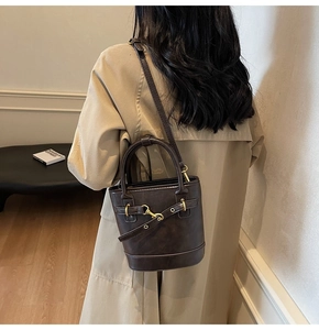 Détail d'un sac seau vintage marron foncé avec bandoulière réglable et détails dorés