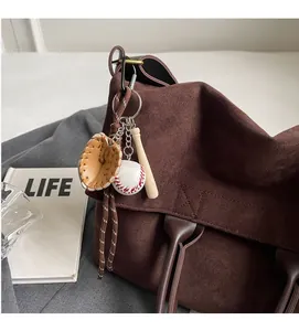 Dettaglio di ciondolo da baseball con guanto e mazza su borsa tote in pelle scamosciata