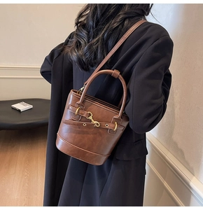 Mannequin portant un sac seau marron foncé vintage avec fermoir doré et bandoulière