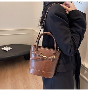 Détail d'un sac seau en cuir marron avec boucles dorées et base renforcée élégante