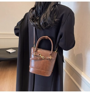 Vue arrière d'un mannequin portant un sac seau vintage en cuir marron et boucles dorées