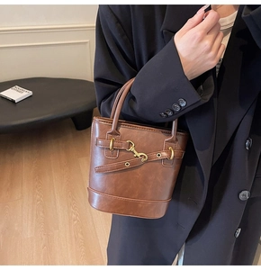 Détail du sac seau vintage marron avec finitions dorées et sangle décorative en cuir
