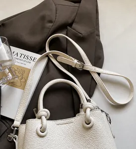 Close-up of a creamy beige lychee grain leather bucket bag with an adjustable shoulder strap