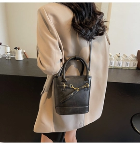Détail du sac seau noir avec garnitures dorées dans un décor de café moderne