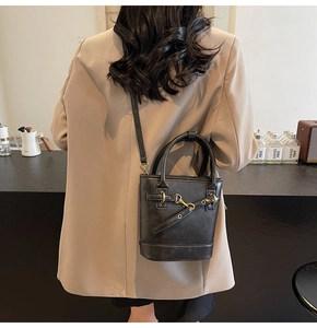 Vue détaillée du sac seau noir avec poignée ronde et finitions métalliques dorées vintage