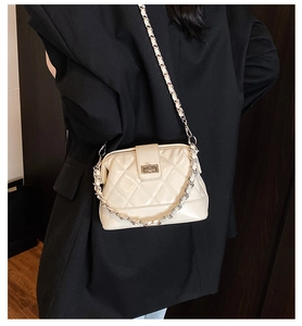 Détail d'un sac bandoulière matelassé crème avec chaîne argentée et fermoir pivotant